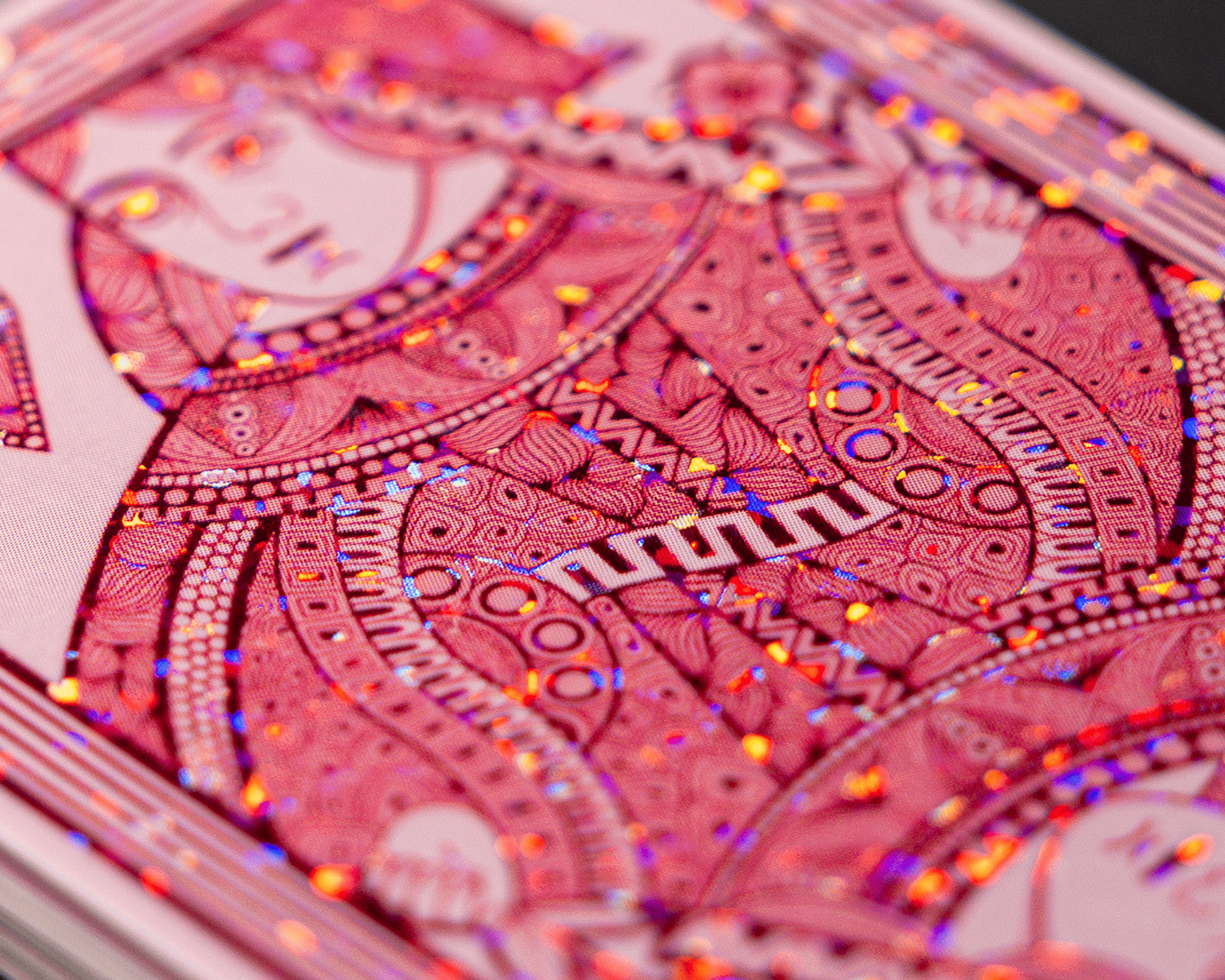 Close-up of a playing card glitter sticker with intricate red and pink patterns, featuring a stylized, abstract figure adorned with colorful glitter dots.